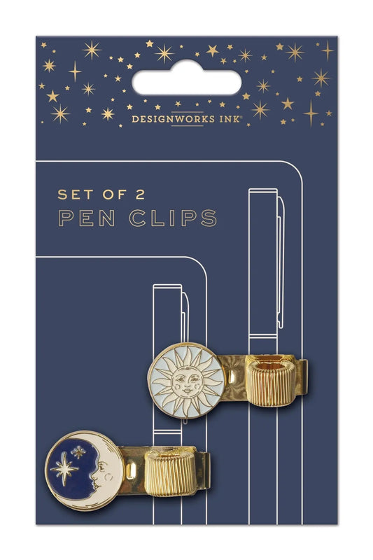 The Set of 2 Pen Clips - Celestial features metallic sun and moon designs on dark blue, star-patterned packaging—ideal for upgrading your journaling routine or adding a celestial touch to your stationery collection.