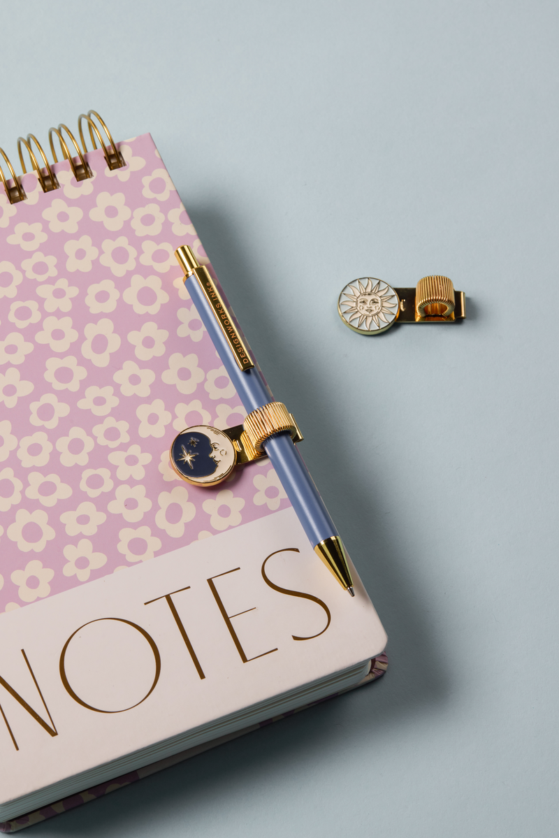 Notebook with floral design and charms on a light blue background