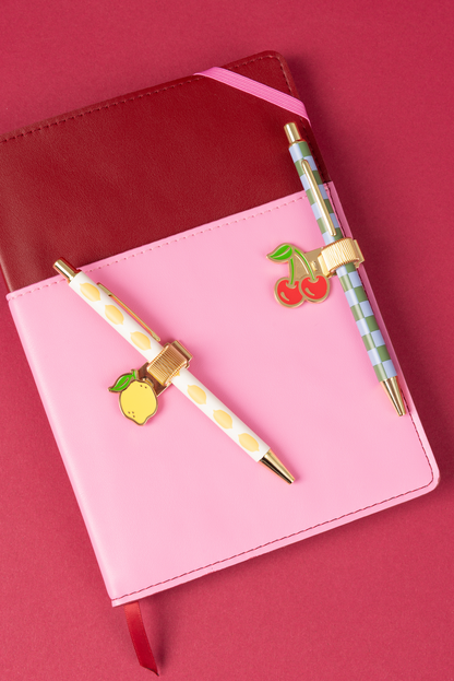 Pink notebook with decorative pen and charms on a red background