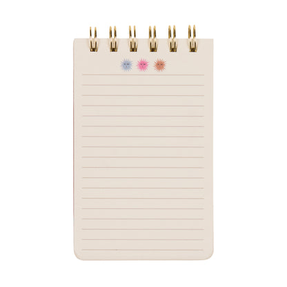 The A Dopo Twin Wire Notepad - Sun is a compact, spiral-bound notepad with lined pages, adorned at the top with three hand-drawn starburst symbols in blue, pink, and red set against a crisp white background. This delightful piece of creative stationery adds a touch of personality to your everyday note-taking.