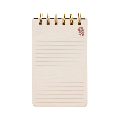 A Dopo Twin Wire Notepad - Tomato: A small, spiral-bound notepad with lined pages and a cluster of red tomatoes in the top right corner, featuring subtle Mediterranean-inspired hand-drawn designs, photographed on a white background.
