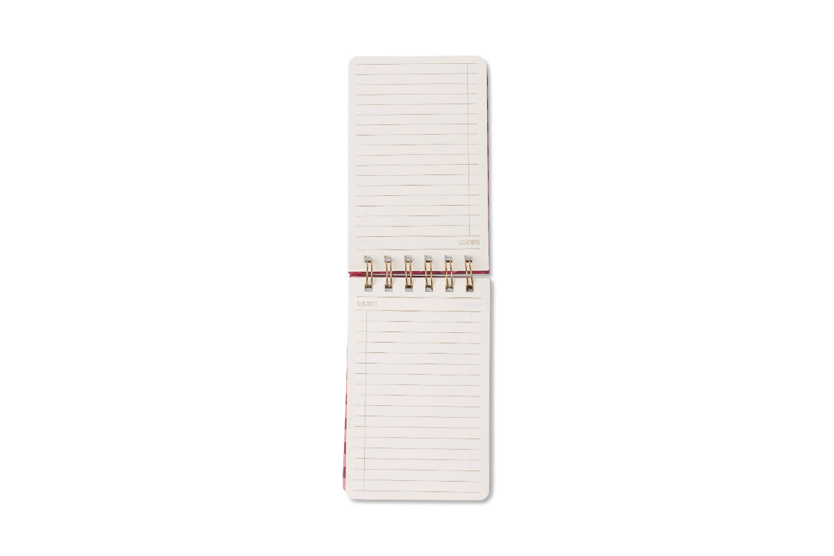 An open Tulip Twin Wire Notepad - Pinwheel Pink with lined, blank pages is seen from above on a white background. The gold-colored spiral binding divides the pages—ideal for jotting notes or sketches.