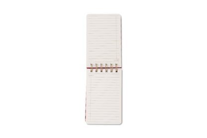 An open Tulip Twin Wire Notepad - Pinwheel Pink with lined, blank pages is seen from above on a white background. The gold-colored spiral binding divides the pages—ideal for jotting notes or sketches.
