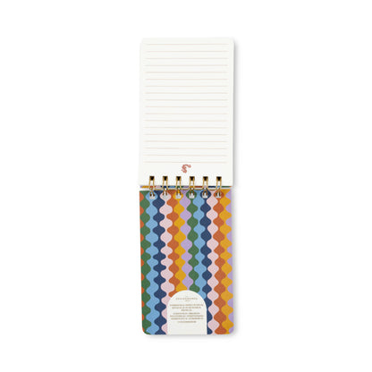 A spiral-bound lined notepad with a colorful geometric patterned cover, shown open against a plain white background.
