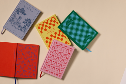 Five colorful notebooks with patterned covers on a beige background