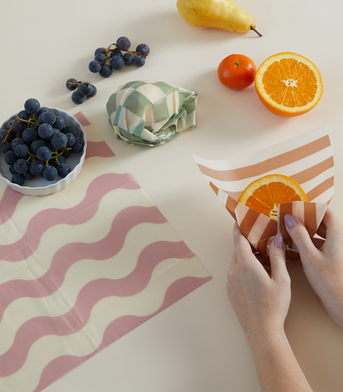 beeswax wraps for food on a white table surrounded by various fruits