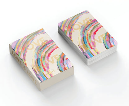 Deck of Love Is Love playing cards resting next to the box on white background; both deck and box have a rainbow design and the words Love Is Love embossed