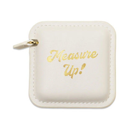 The Pocket Tape Measure - Measure Up is a square, white vegan leather pouch with a zipper and "Measure Up!" in gold cursive on the front.
