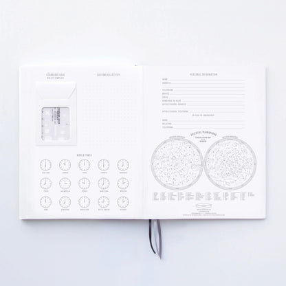The Standard Issue Notebook No.3 - Blue opens to show personal info fields, world time clocks, cultural planisphere maps, and a wallet template on the left page—all designed for a premium writing experience with quality construction.