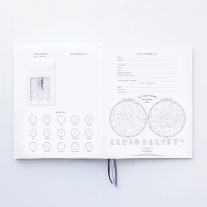 The Standard Issue Notebook No.3 - Green is an open planner with a world clock chart, celestial planispheres, space for personal info, and a clear card insert—crafted for a premium writing experience with high-quality construction.