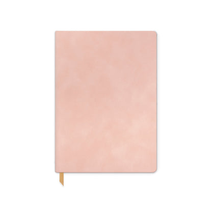 The Vegan Suede Journal - Dusty Blush is a closed, light pink notebook with a vegan suede cover, rounded corners, and a gold ribbon bookmark, shown against a white background.