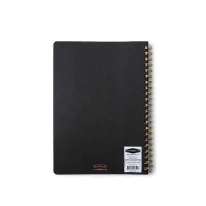 A closed Textured Paper Twin Wire Notebook - Large Ebony is displayed with a gold twin wire spiral binding and a white barcode sticker on the lower right corner of its softcover front.
